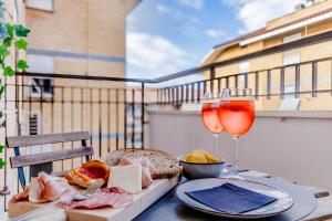 罗马LoungeFloor Metro A Netflix & Wi-Fi的阳台上的桌子上放着两杯葡萄酒和食物