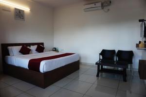 班加罗尔Vistar Resort & Hotels的配有一张床和一把椅子的酒店客房