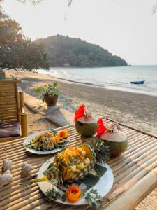 昌岛Full Moon Bungalow Resort Koh Chang Ranong的海滩上餐桌上的两盘食物