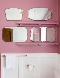 锡豪西斯Pebble Cottage的浴室设有粉红色墙壁上的三面镜子