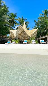 ThinadhooThari Fushi Luxury Maldivian Experience - All Inclusive的一个带椅子的海滩和一个棕榈树度假村