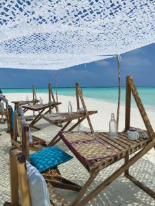 ThinadhooThari Fushi Luxury Maldivian Experience - All Inclusive的海滩上的一组桌椅