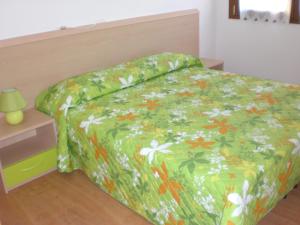 利多迪耶索罗Villa Nicole 2 camere的一张带绿棉被和鲜花的床