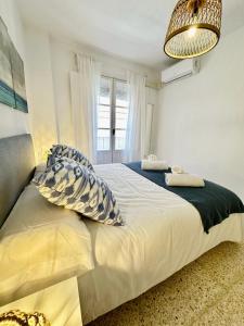 加的斯www Casa Quili Cádiz com的卧室配有带枕头的床铺和窗户。