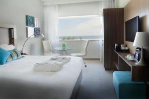 格丁尼亚格丁尼亚海滨万怡酒店的酒店客房设有一张白色大床和一个窗户。