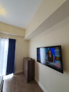 宿务Arlowes Cebu at 20f Grand Residences Cebu的客厅的墙上配有平面电视。