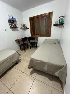 卡庞达卡诺阿Legítima casa de praia的卧室配有一张床和一张桌子及椅子