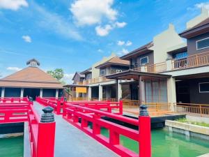 Nang RongCOZY SHIROI RESORT的一座水面上的红桥,在一些建筑物前