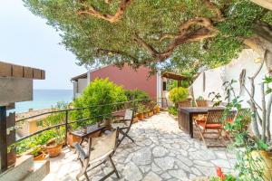 格利法达Athena's Veranda magestic views in Glyfada beach of Corfu by New Era的树下带桌椅的天井