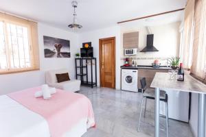 格拉纳达Apartamentos Granata的厨房以及带粉红色桌椅的起居室。