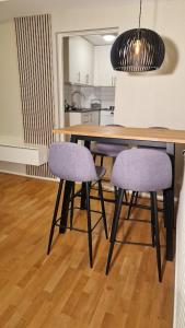 哥德堡Mysigt Stadsoas: En Modern lägenhet med 2 sovrum的餐桌、两把紫色椅子和厨房