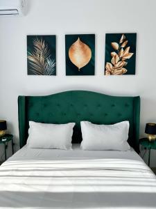 布拉索夫KOA - Moon Penthouse的一间卧室配有绿色床头板和四幅墙上的照片