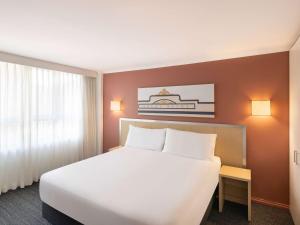 纽卡斯尔Mercure Newcastle的酒店客房设有一张白色大床和一个窗户。