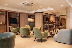 若昂佩索阿HCM - Hotel Corais de Manaira的一间设有绿色桌椅的餐厅和一间酒吧