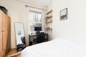伦敦Charming Victorian 1BR Retreat in the Heart of London的一间卧室配有一张床、一张书桌和一面镜子