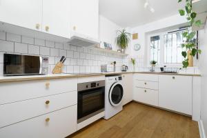 伦敦Lovely Apartment in Victoria Park Village的厨房配有白色橱柜、洗衣机和烘干机