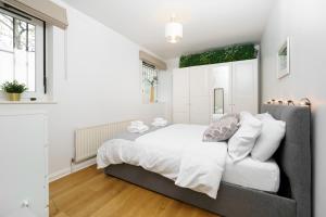 伦敦Lovely Apartment in Victoria Park Village的白色的卧室设有一张大床和一个窗户