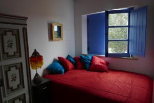 维拉多比斯坡Barranco do Zambujeiro的一间卧室设有红色的床和窗户。
