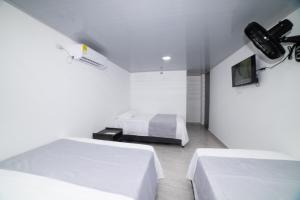 圣玛尔塔Hotel Santa Marta Tropical的一间白色卧室,配有两张床和电视