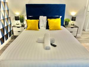 伯恩茅斯Sleek Urban Getaway - With Parking的一张白色的床,配有黄色枕头和蓝色床头板