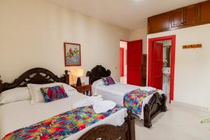 贾丁Hotel Casa Grande的一间卧室设有两张床和红色的门