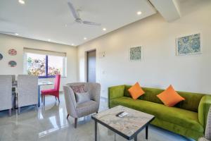 坎多林Premium 2BHK Apartment with pool at Candolim Beach的客厅配有绿色沙发和桌子