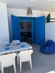 海尔盖莱Villa dar nina hergla的蓝色门的房间的桌椅