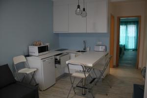 坎普自由鎮Vila Mar的厨房配有白色橱柜和桌椅