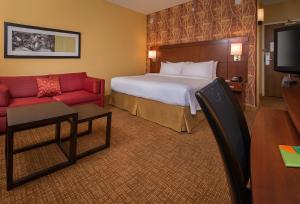 威廉斯堡威廉斯堡布希花园万怡酒店的酒店客房,配有一张床和一张红色的沙发