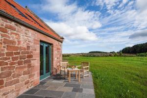 East LintonPloughman's Bothy at Papple Steading的砖砌建筑的庭院配有两把椅子和一张桌子