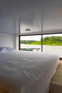 托尔图格罗Hotel Pura Natura Riverside Tortuguero的一间卧室设有一张大床和一个大窗户