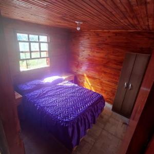 巴拉德尔楚Cabaña El Mar的木制客房内的一间卧室配有一张紫色的床