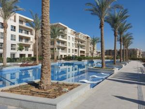开罗Alumia Marigold Suite 3BR Apt Pool Access的一座楼前棕榈树游泳池