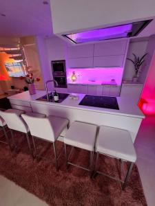 隆德泽尔Relax House B&B Londerzeel的厨房设有酒吧,配有白色椅子和紫色照明