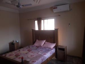 Sukuta3 bedrooms first story apartment的一间卧室配有带粉红色枕头的床和窗户。