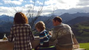 LlenínHeredad de la Cueste的两位成年人和一名儿童坐在桌子旁,俯瞰群山