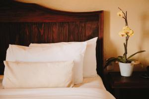 圣克里斯托瓦尔-德拉斯卡萨斯Docecuartos Hotel的一张带白色枕头的床和一张带鲜花的花瓶。