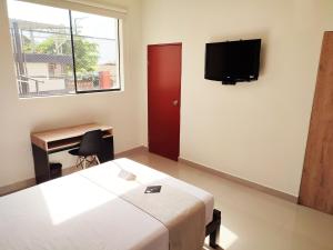 塔拉拉Rua Hoteles Talara的卧室配有一张床,墙上配有电视。