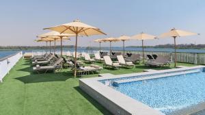 阿斯旺book Now Nile Cruise From Aswaon every Friday & Monday & wednesday Included Tours的水边带椅子和遮阳伞的游泳池