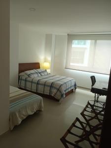 卡塔赫纳Cartagena Beach Condo - 1400 sq. Ft. (130 m2)的一间卧室配有一张床、一张书桌和一个窗户。