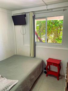 弗洛里亚诺波利斯Casa beira do mar的一间卧室设有一张床、一个窗口和一张红色的桌子