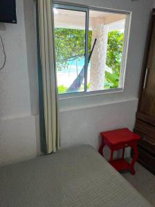 弗洛里亚诺波利斯Casa beira do mar的一间卧室设有一张床和一个带红色凳子的窗户