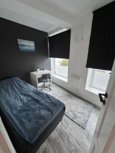 卑尔根Spacious and Beautiful Apartment in Bergen with free parking的一间卧室配有一张床、一张书桌和两个窗户。