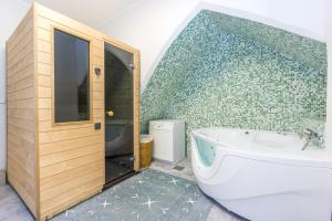 塔林Exclusive House in Old Town的带浴缸的浴室和绿色瓷砖墙
