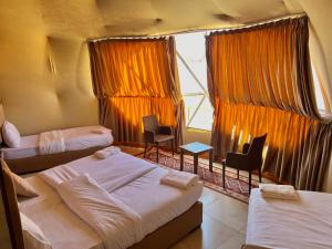 瓦迪拉姆Wadi Rum living camp的带三张床和椅子的房间以及窗户