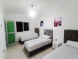 丹吉尔Fantastique Appartement Nouveau meublé avec WIFI & NETFLIX à proximité du MARJANE M2的配有2张床的白色墙壁和窗户客房