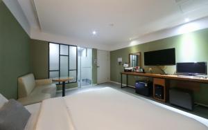 釜山Yeonsan Oops Hotel的酒店客房设有一张大床和一台电视。