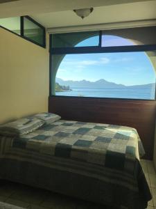 帕纳哈切尔Apartamento Torres de Atitlan的一张位于带大窗户的房间内的床铺