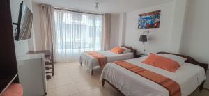 新洛哈Hotel Israel - Lago Agrio的酒店客房设有两张床和窗户。