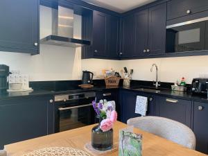 GamlingayPrivate Apartment at Woodland Retreat的厨房配有海军蓝的橱柜和木桌